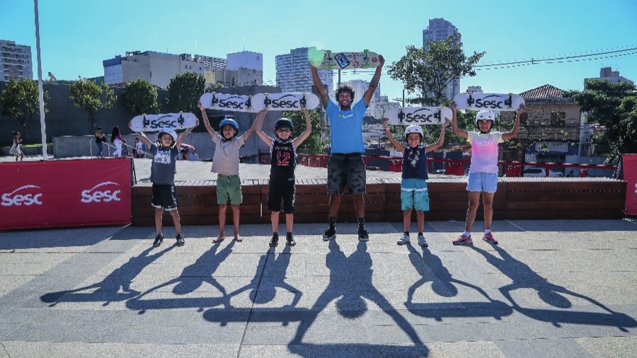 Crianças com skates erguidos em ação no Sesc Belenzinho