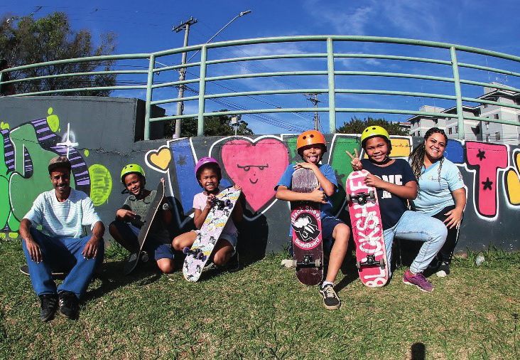 Crianças com skates em frente ao muro grafitado