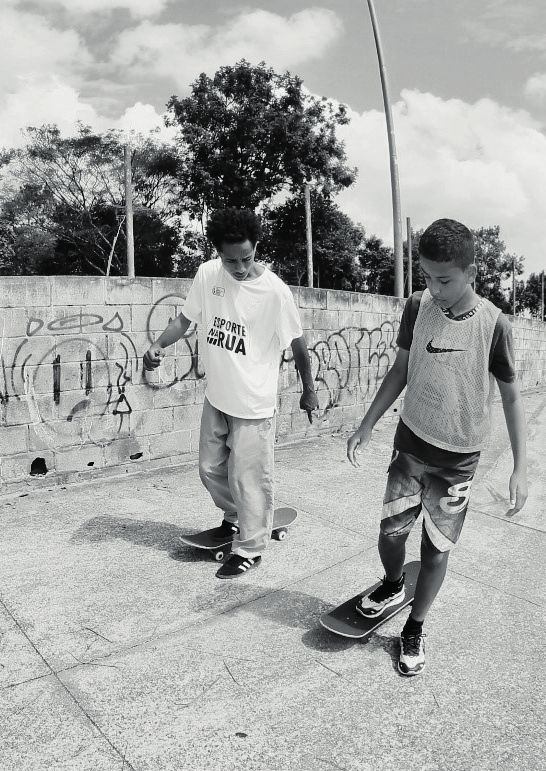 Duas crianças andando de skate em preto e branco